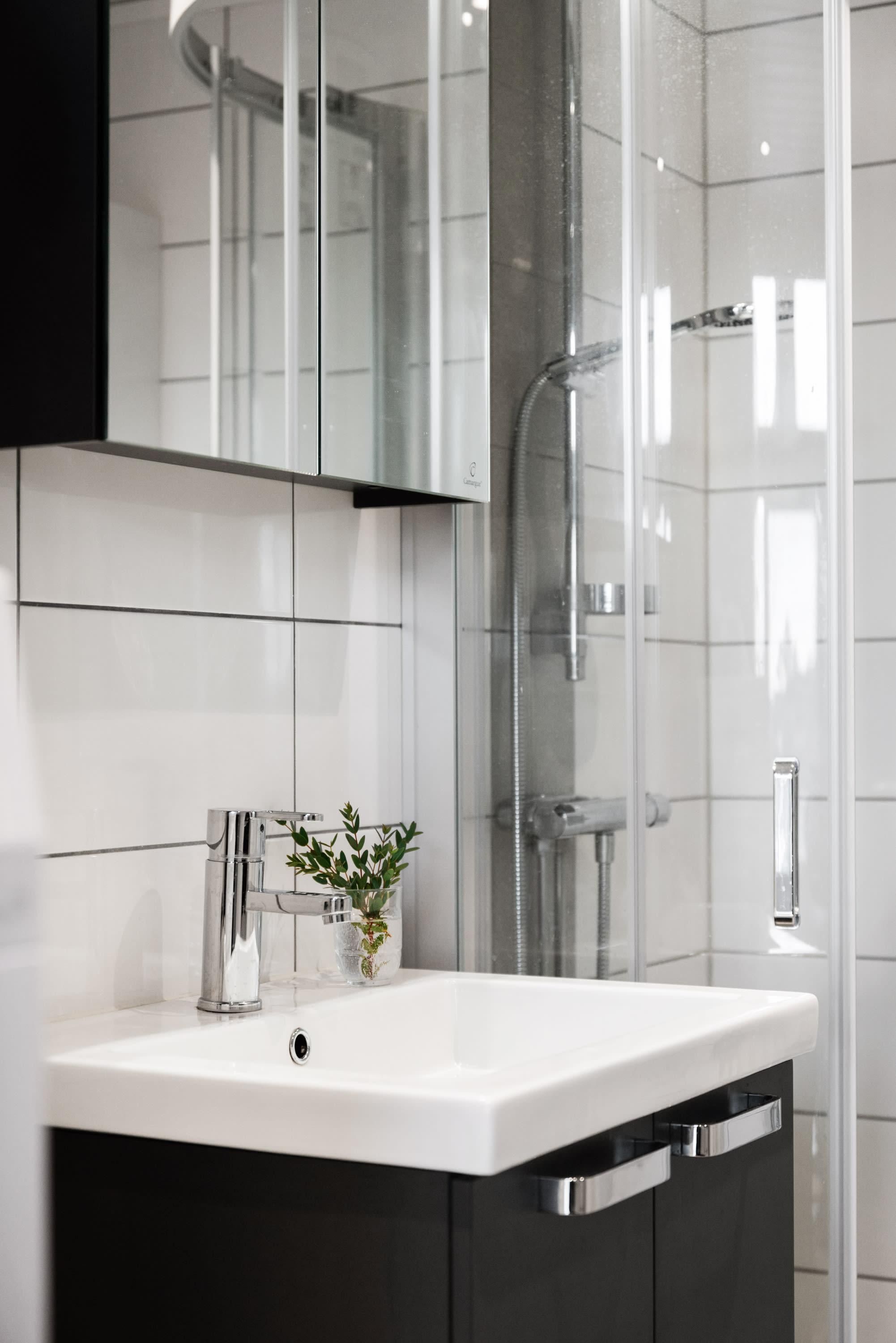 A modern bathroom with a white sink, chrome fixtures, and a glass shower enclosure.