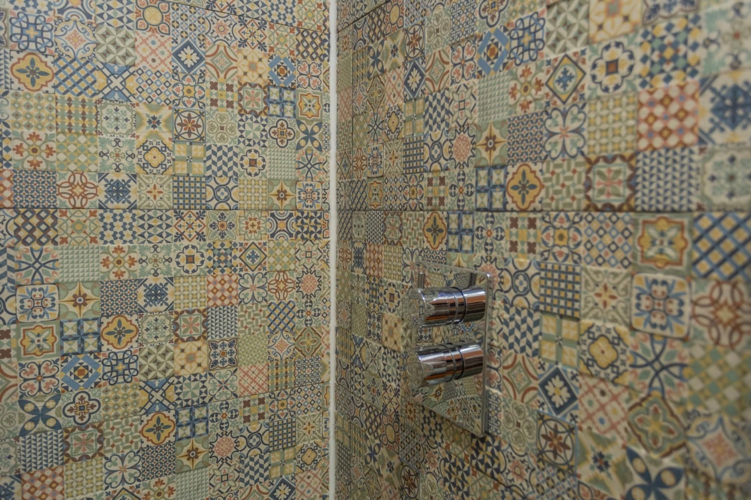 Baño con pared de azulejos que presenta una variedad de diseños geométricos y florales.