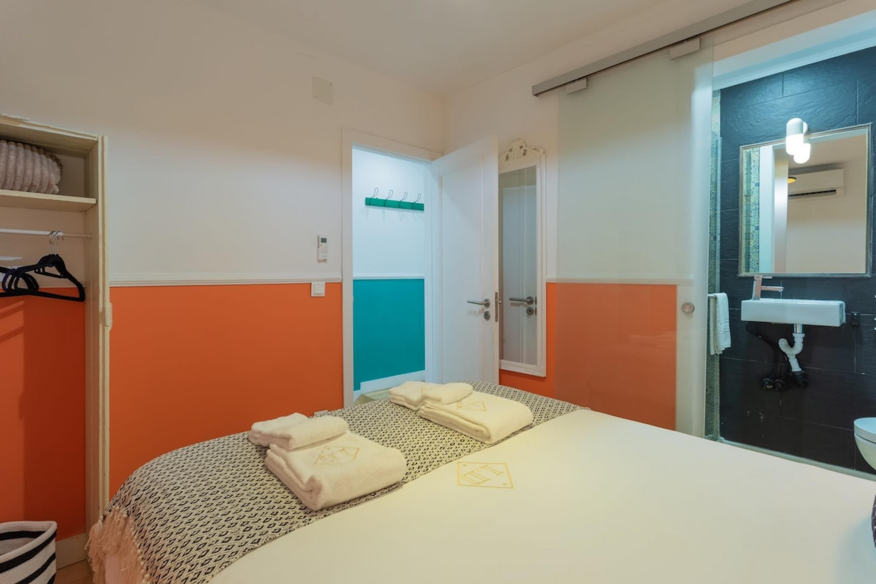 A hotel room with a bed, a bathroom with a sink and mirror, and a door leading to another room.