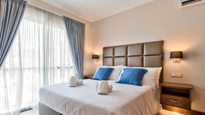 Una habitación de hotel con una cama grande, dos mesitas de noche y una mesilla.