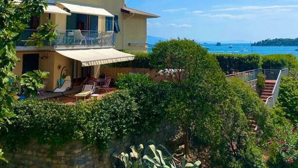 A two-story building with a balcony and outdoor seating area, overlooking a body of water. - Rebecca s Portovenere Collection (Portovenere)