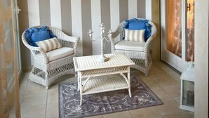 A room with two wicker chairs, a small table, and a striped wall. - Rebecca s Sanremo Collection I (Sanremo)