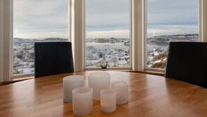 A room with a large window, a wooden table with candles, and a vase. - Vetteberget Huset in Fj Llbacka (Fjallbacka)
