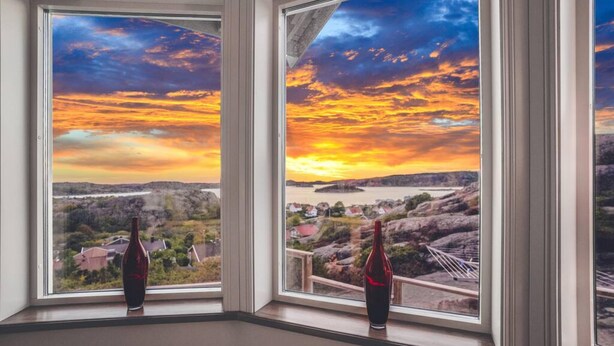 A room with a large window overlooking a scenic landscape during sunset. - Vetteberget Huset in Fj Llbacka (Fjallbacka)