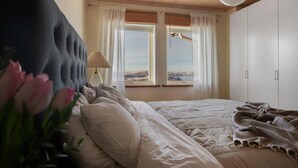 A bedroom with a bed, a window with curtains, a lamp, and a view of the outside. - Vetteberget Huset in Fj Llbacka (Fjallbacka)