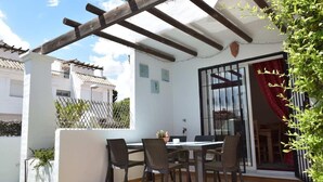 A patio with a table and chairs, a pergola, and a sliding glass door.