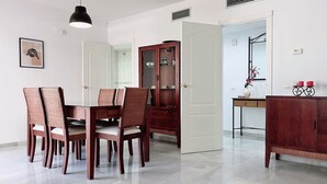 A dining area with a wooden table and chairs, a cabinet, and a mirror on the wall. - Spacious Poolside 3 Bedroom F-5 (Marbella)