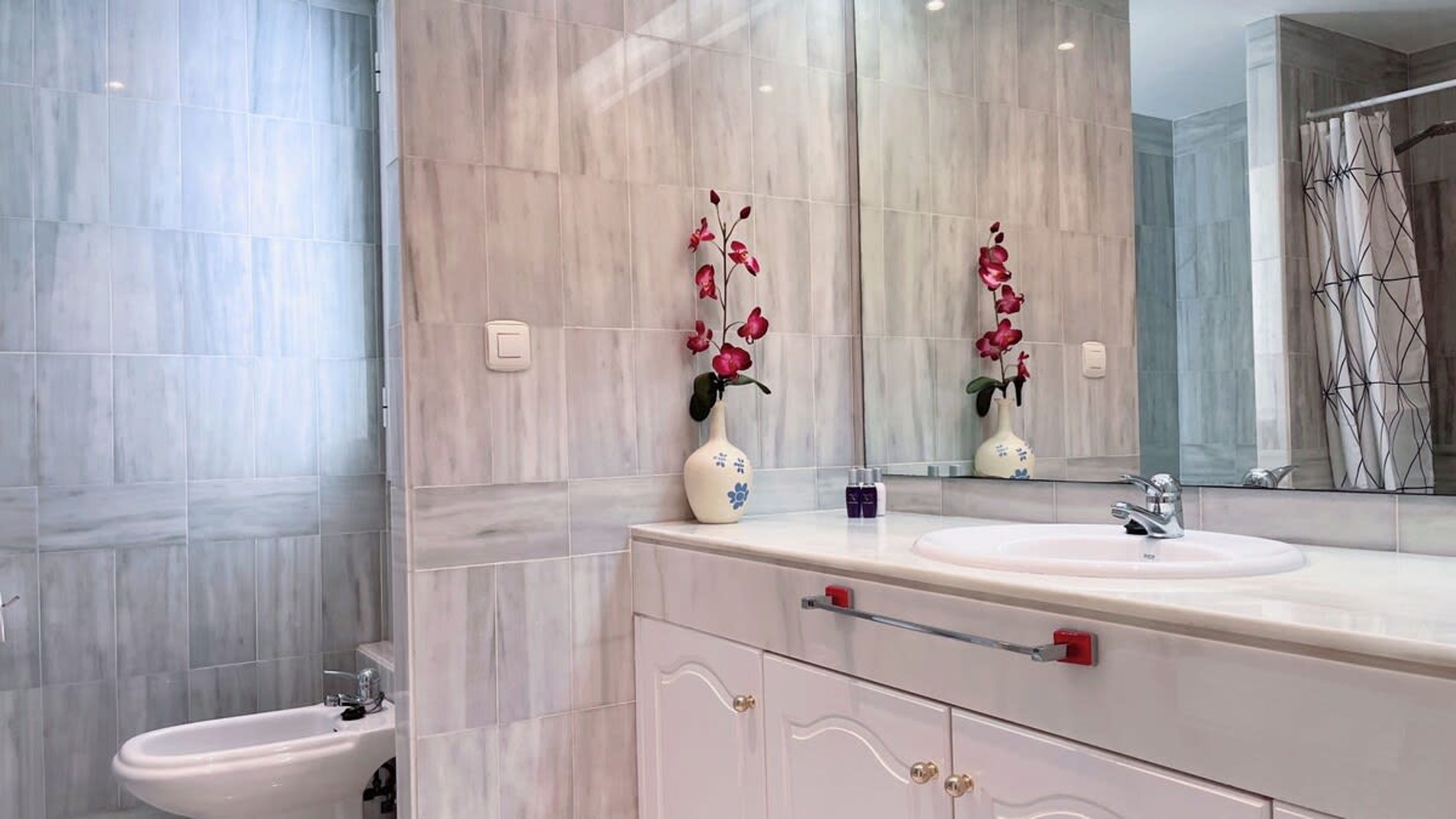 A modern bathroom with a marble vanity, a sink, and a bidet.