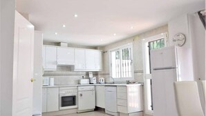 A modern kitchen with white cabinets, a built-in oven, a dishwasher, and a refrigerator. - Villa Emma 4 Bedrooms F-3 (Marbella)