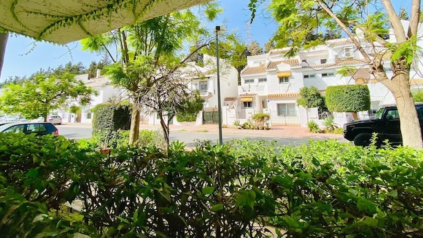 Un barrio residencial con casas blancas, un corredor cubierto y zonas verdes.