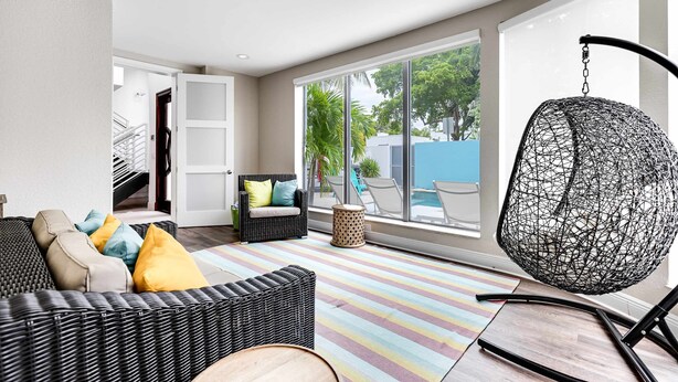 Ein modernes Wohnzimmer mit einem Korbssessel, einem Hängesessel und einem farbenfrohen Streifen Teppich.