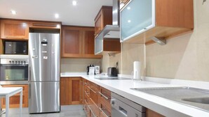 Una cocina moderna con armarios de madera, electrodomésticos de acero inoxidable y encimera blanca.
