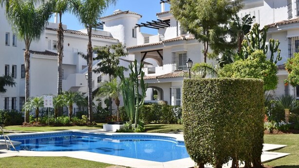 A pool area with a clear blue pool, surrounded by palm trees and a neatly trimmed hedge. - 3 Bed Excellent and Quiet Location F-4 (Marbella)