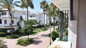 A residential area with white buildings, palm trees, and a paved walkway. - Bright 2 Bedroom First Floor F-4 (Marbella)