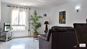 A living room with a sofa, a TV on a stand, a potted plant, and artwork on the wall. - Bright 2 Bedroom First Floor F-4 (Marbella)