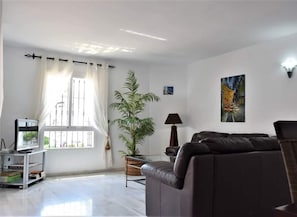 A living room with a sofa, a TV on a stand, a potted plant, and artwork on the wall. - Bright 2 Bedroom First Floor F-4 (Marbella)