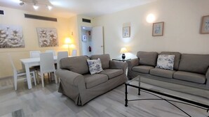 Una sala de estar con dos sofás, una mesa de centro y un comedor con sillas y una mesa.