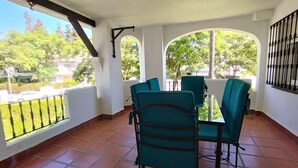 Un patio cubierto con una mesa y sillas, ventanas amplias y vistas al exterior.