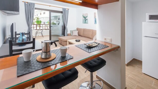 Una cocina moderna con encimera de madera, cafetera y refrigerador.