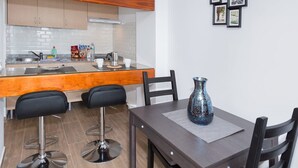 Una cocina moderna con armarios de madera, encimera de granito y un comedor con mesa y sillas.