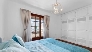 A bedroom with a bed, curtains, a window, and a wardrobe.