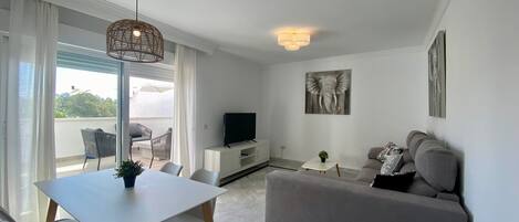 Un soggiorno moderno con zona pranzo, un divano grigio, una TV a schermo piatto e opere d'arte alle pareti.