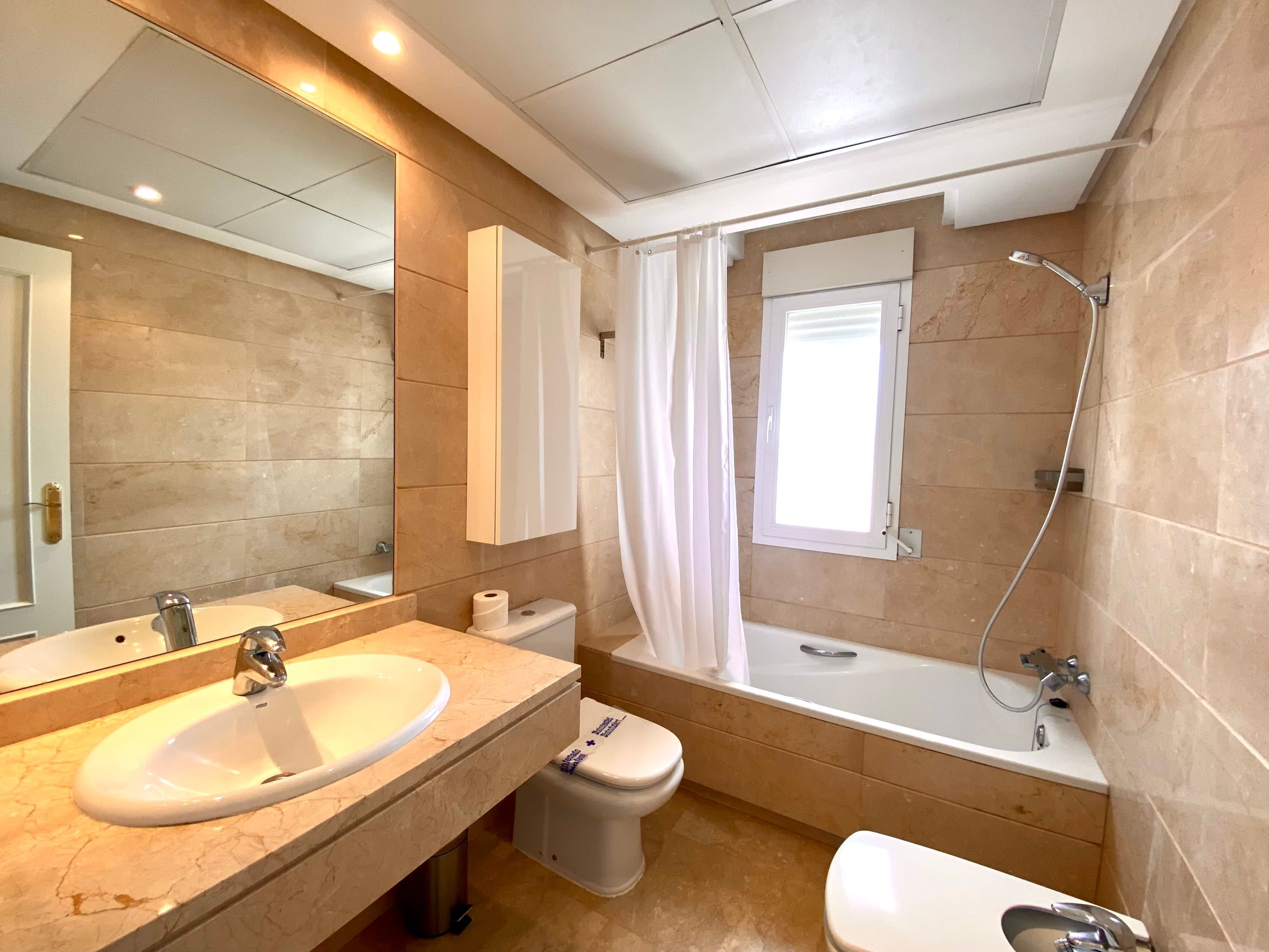 Een moderne badkamer met een wastafel, toilet en bad.