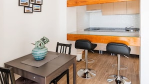 A modern kitchen with wooden cabinets, a stainless steel countertop, and a bar area with two black bar stools. - Apartamento Golden Teguise 2 (Alcorcon)