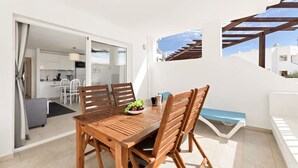Een houten eettafel met stoelen, een schaal fruit en een blauwe bank.