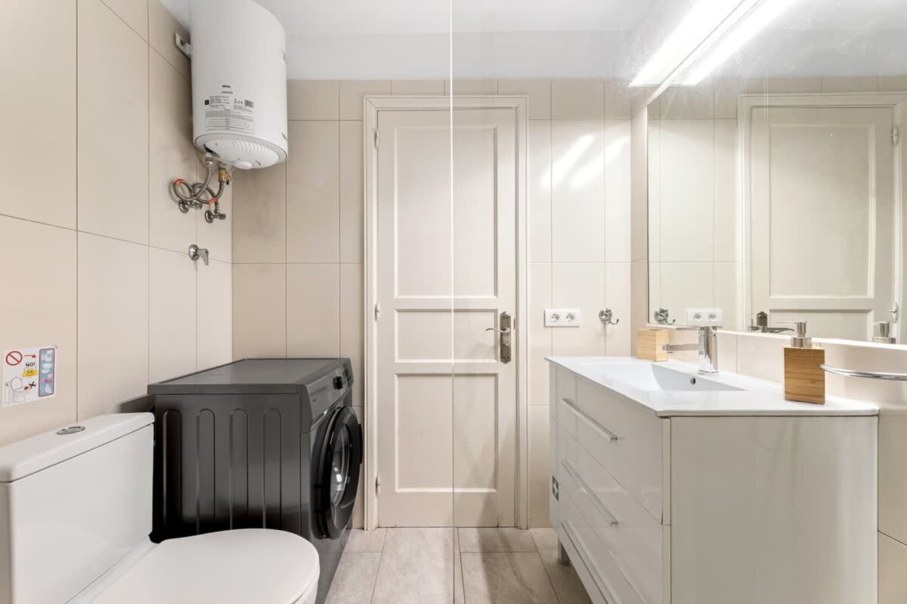 Une salle de bain moderne équipée de toilettes, d’un lave-linge et d’un lavabo avec un miroir.