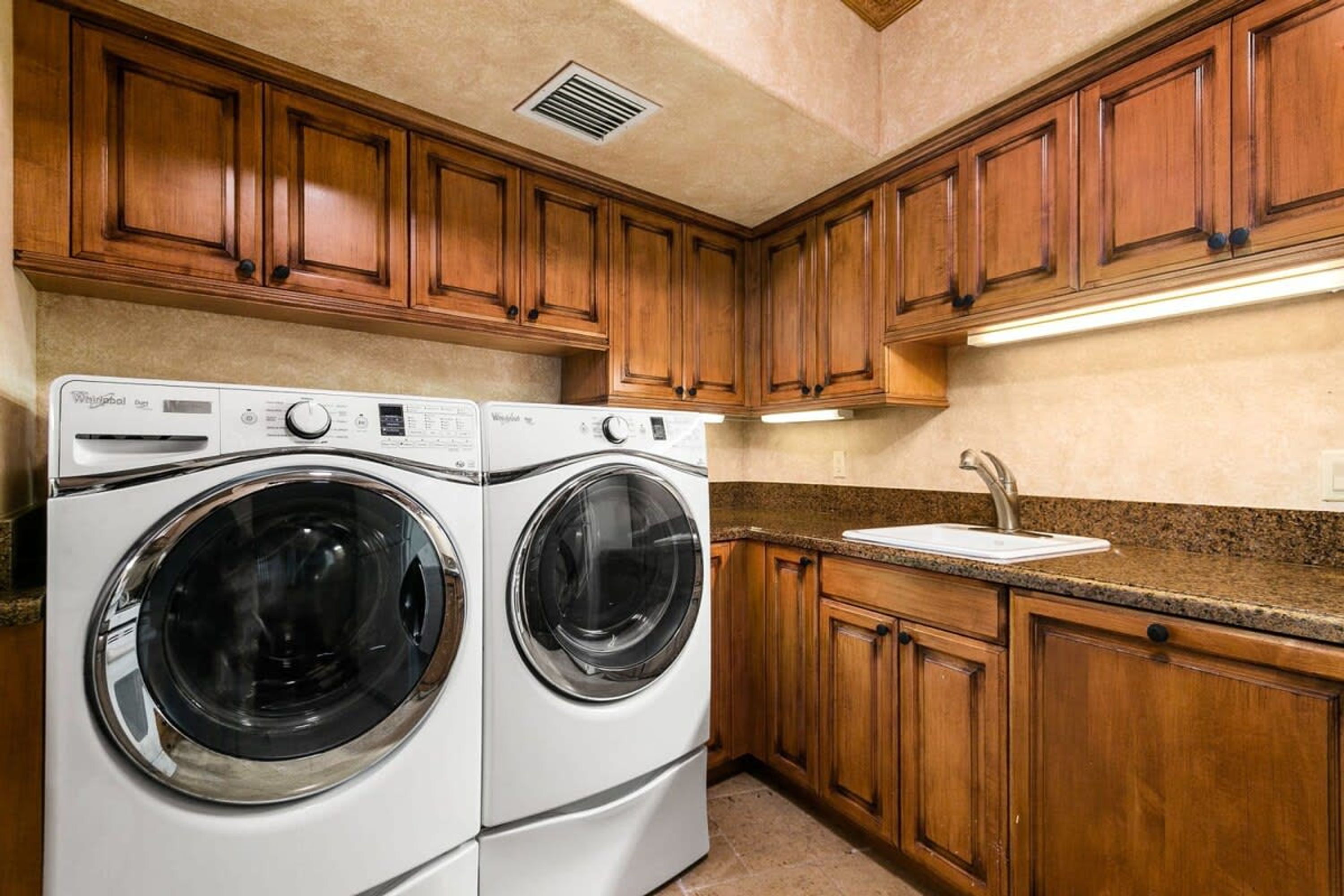 A kitchen with wooden cabinets, a double washer, and a sink.