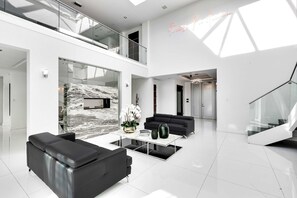 Un intérieur moderne avec un mur en marbre, un canapé en cuir noir et un escalier en verre.