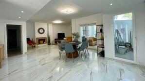 Amplia sala de estar con mesa de comedor, asientos cómodos, televisor de pantalla plana y chimenea.
