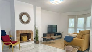 Una sala de estar moderna con chimenea, un sofá, un televisor y un comedor.