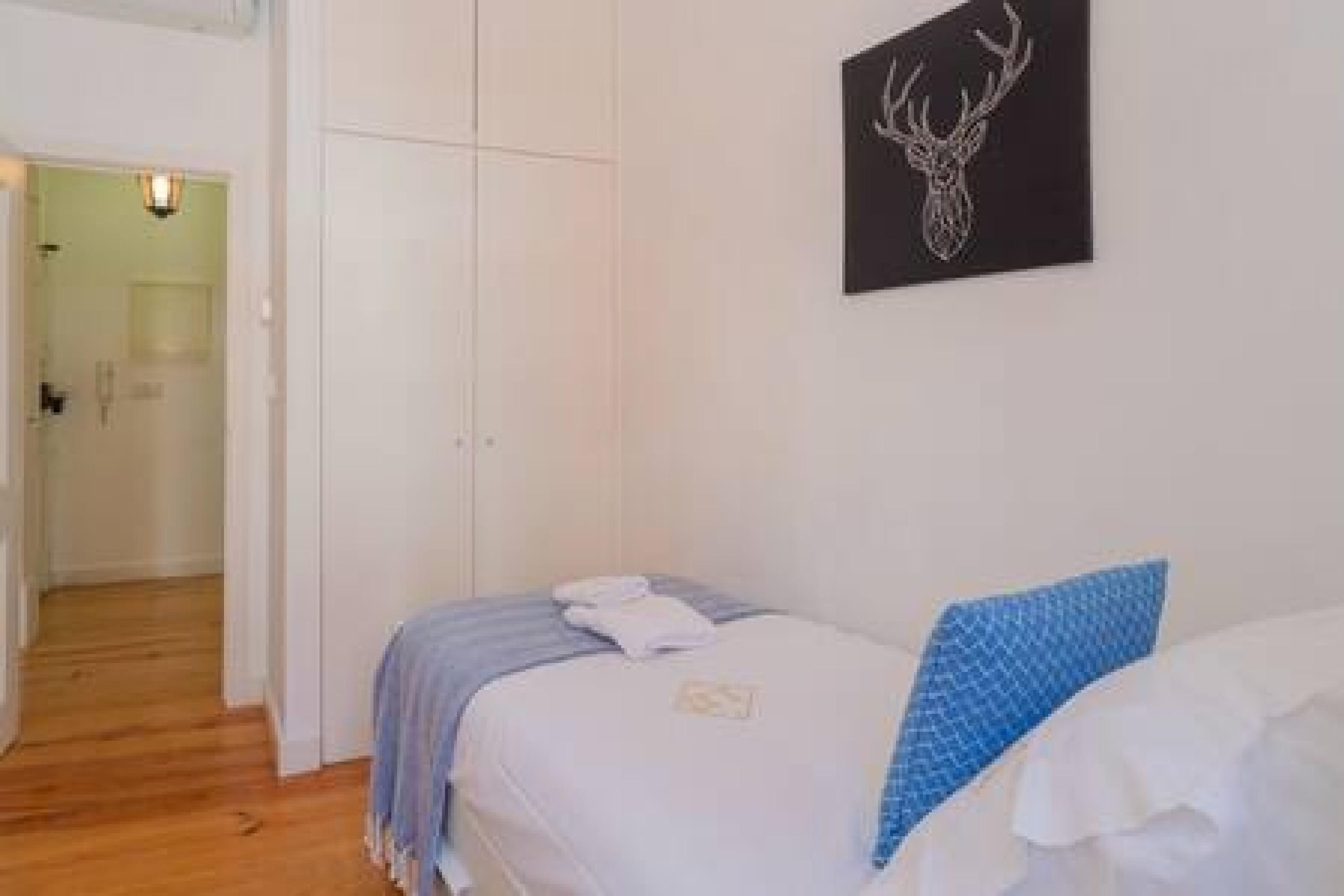 A bedroom with a bed, a wardrobe, and a wall-mounted deer head artwork.