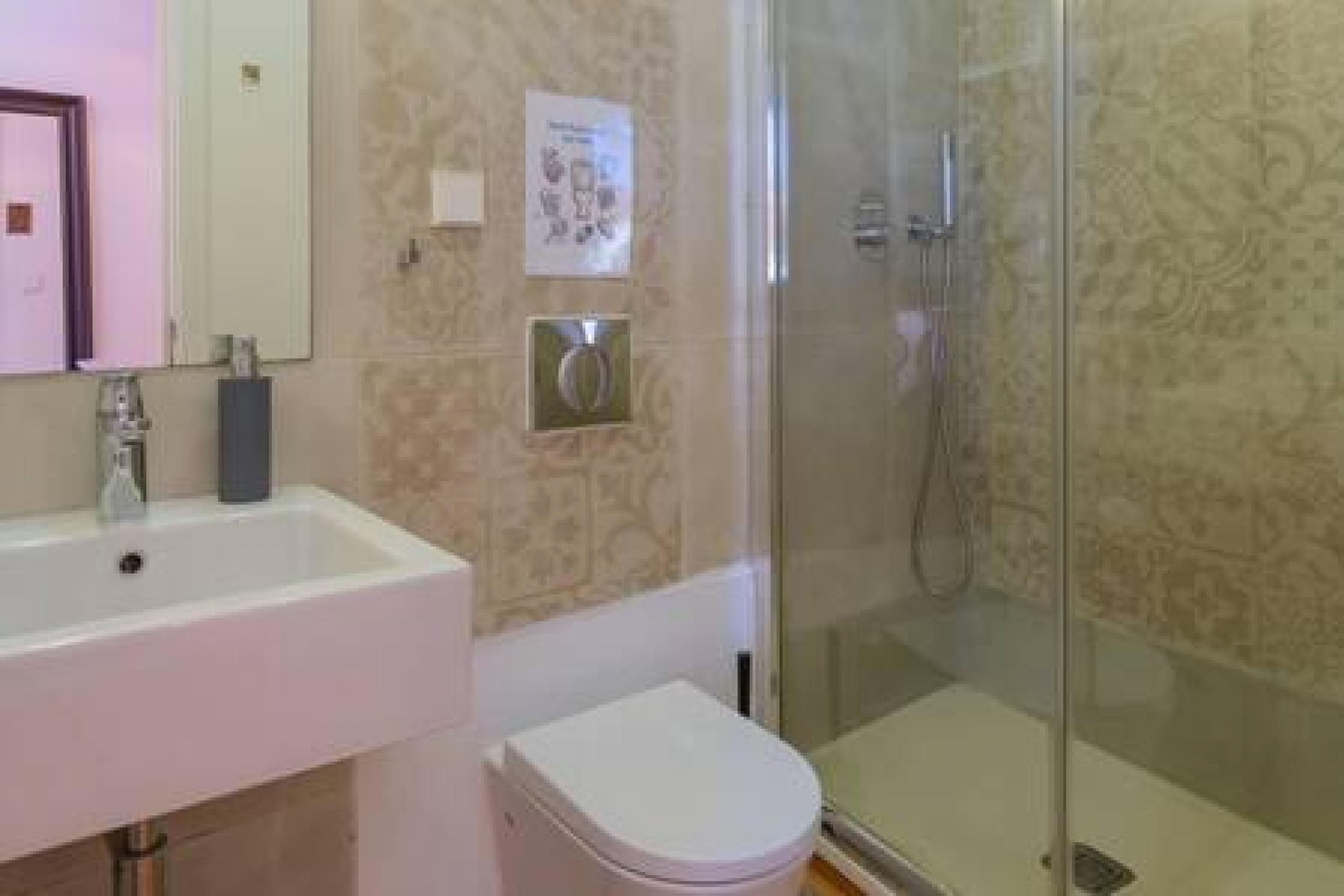 Ein Badezimmer mit weißem Waschbecken, einer Toilette und einer Duschkabine aus Glas.