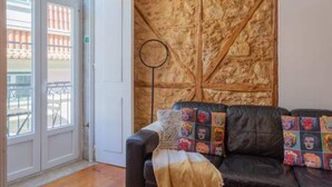 A room with a leather sofa, a patterned wall, and a door leading outside. - Old Town Chiado Balcony Aircon by LD Apartments (Lisbon)