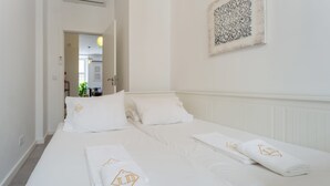 Habitación de hotel con una cama grande, dos almohadas y una toalla doblada con un logotipo.