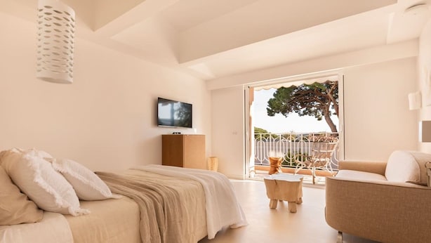 A bedroom with a bed, a sofa, a TV, and a balcony with a tree. - Carla Rosa 11 Luxueux Studio Piscine - 1bdr (Cannes)