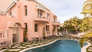 A pool area with a curved pool, lounge chairs, and a building with balconies. - Carla Rosa 11 Luxueux Studio Piscine - 1bdr (Cannes)