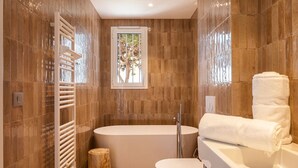 A modern bathroom with a freestanding bathtub, a toilet, and a towel rack. - Carla Rosa 11 Luxueux Studio Piscine - 1bdr (Cannes)