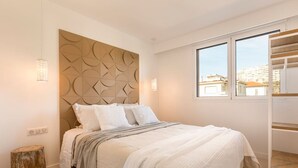 A modern bedroom with a geometric headboard, a large window, and a built-in closet. - Carla Rosa 10 Luxueux Appartement Piscine -2 BDR (Cannes)