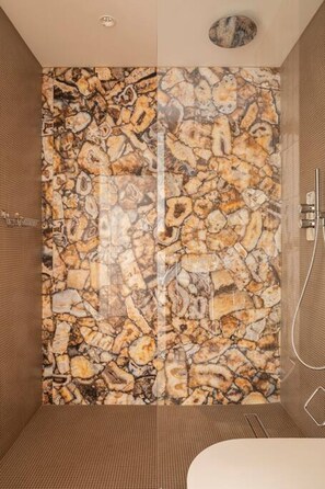 A bathroom with a stone wall, a shower, and a bathtub.