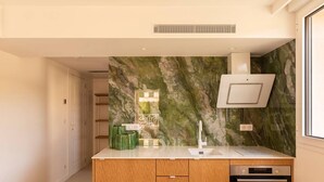 Uma cozinha moderna com painel de parede em mármore, forno embutido e armários de madeira.