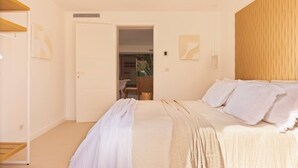 Quarto com uma cama, um guarda-roupa de madeira e uma porta que dá para outro cômodo.
