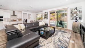 A modern living room with a black leather sofa, a glass coffee table, and a large rug. - Allura Champagne New in Wine Country Pool Game Rm (Winchester)