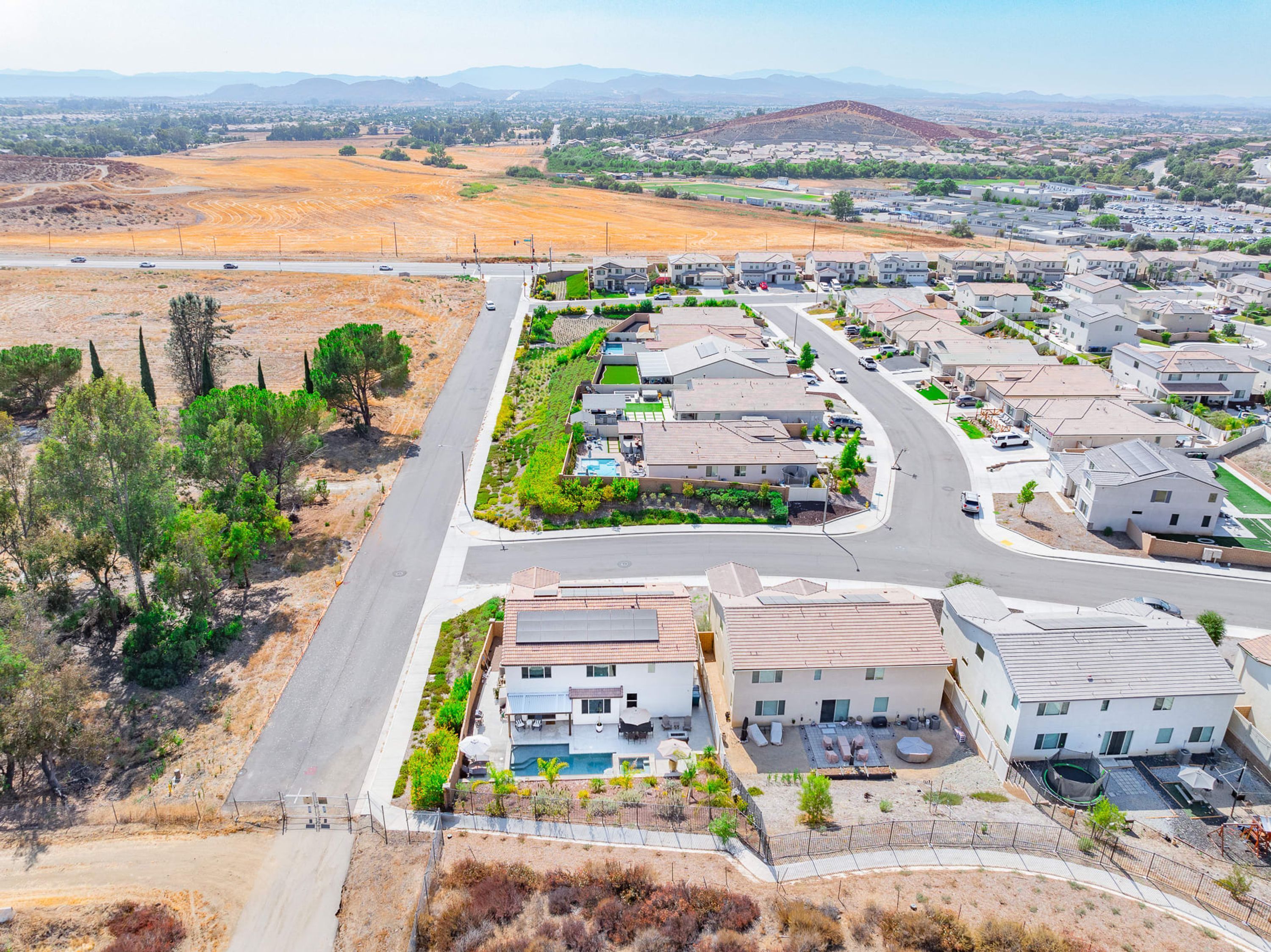 An aerial view of a residential area with houses, roads, and a large open field.