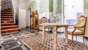 Ein Zimmer mit Schachbrettfußboden, einem runden Tisch, einem Stuhl, einer Treppe und einer Tür.