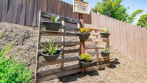 A wooden planter with multiple pots of plants against a wooden fence. - Lux - Charming San Marcos 2BR Patio Pet-friendly (San Marcos)