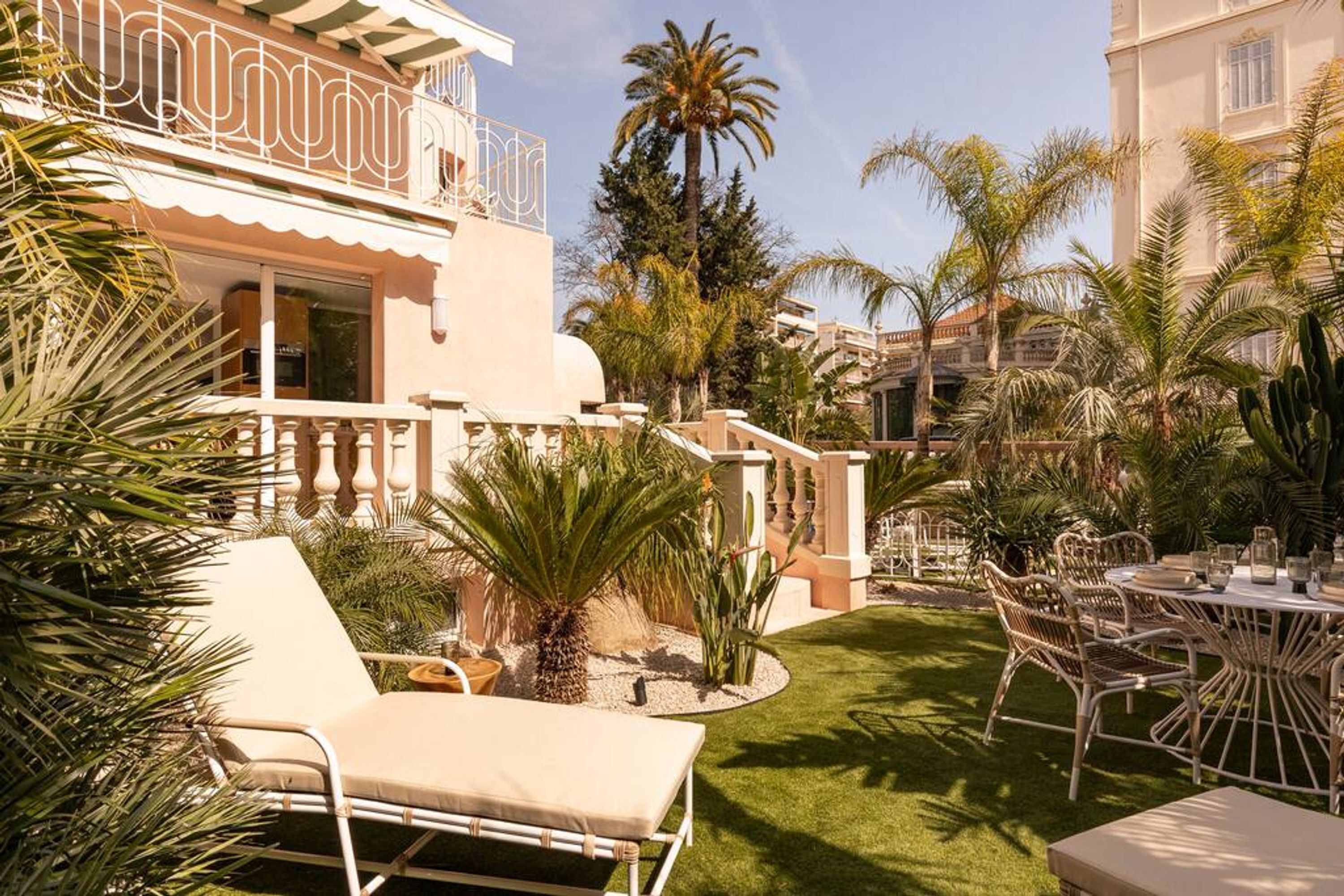 A well-maintained outdoor patio area with a dining set, lounge chairs, and a small palm tree.